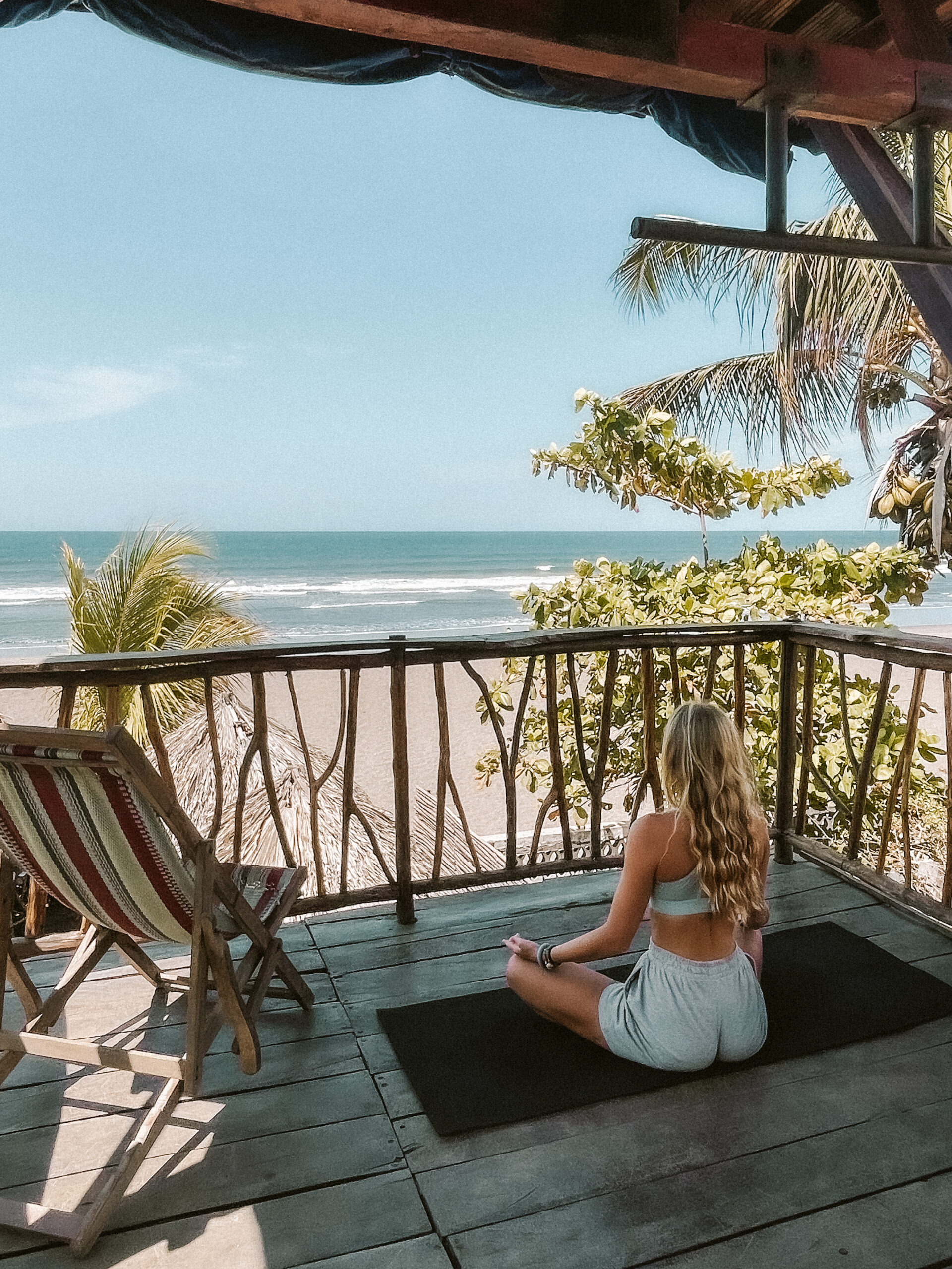 women in lotus pose meditating in front of ocean